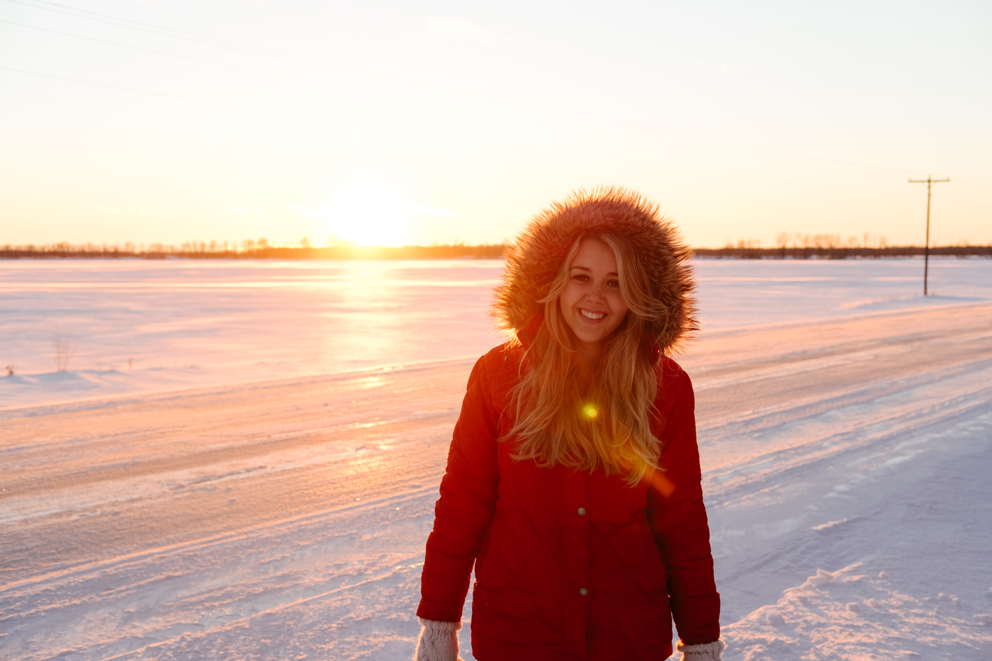 Debora Dahl wearing a red coat in the snow with the sunset behind her